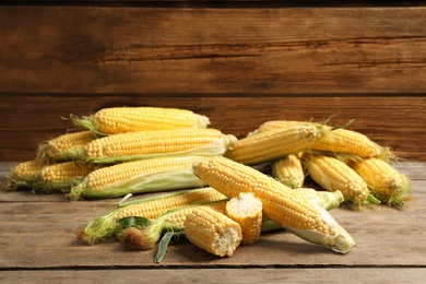 Photo of Tasty sweet corn cobs on wooden table