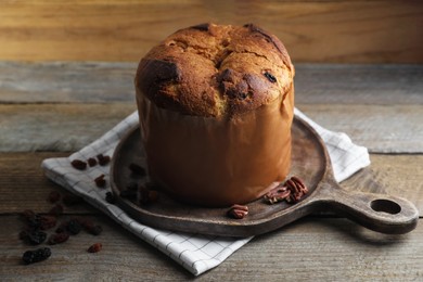 Photo of Delicious Panettone cake, walnuts and raisins on wooden table. Traditional Italian pastry