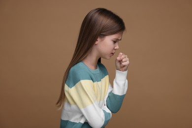 Sick girl coughing on brown background. Cold symptoms