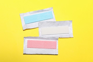 Unwrapped sticks of tasty chewing gum on yellow background, flat lay