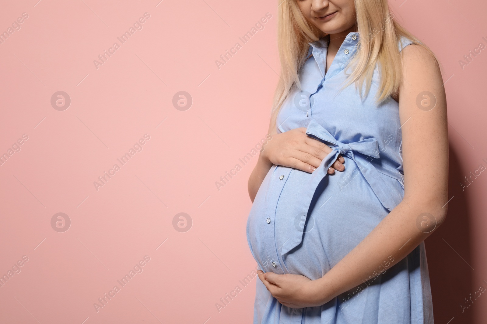 Photo of Pregnant woman in dress on color background. Space for text