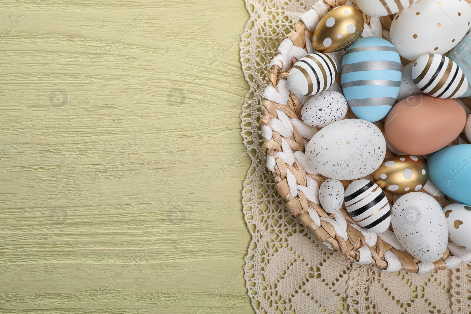 Photo of Many beautifully decorated Easter eggs on yellow wooden table, top view. Space for text