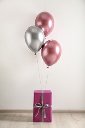 Photo of Gift box and balloons near white wall