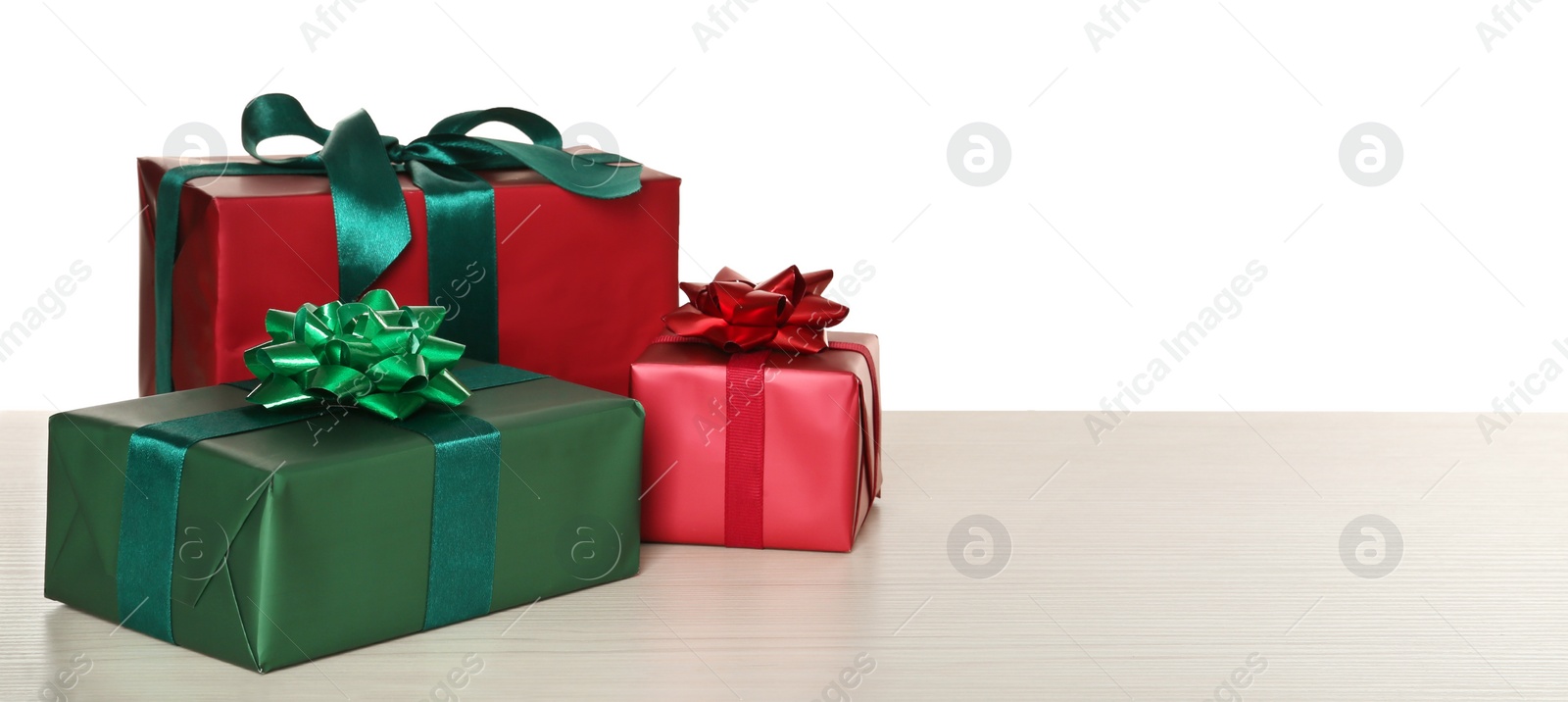 Photo of Red and green gift boxes on wooden table against white background, space for text