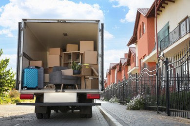 Van full of moving boxes and furniture near house