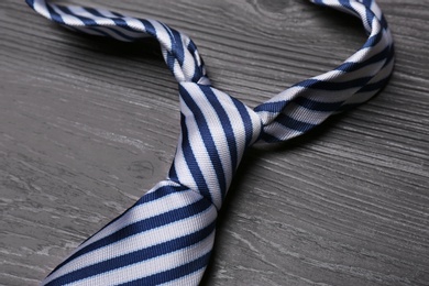 Photo of Stylish striped silk male necktie on dark grey wooden table