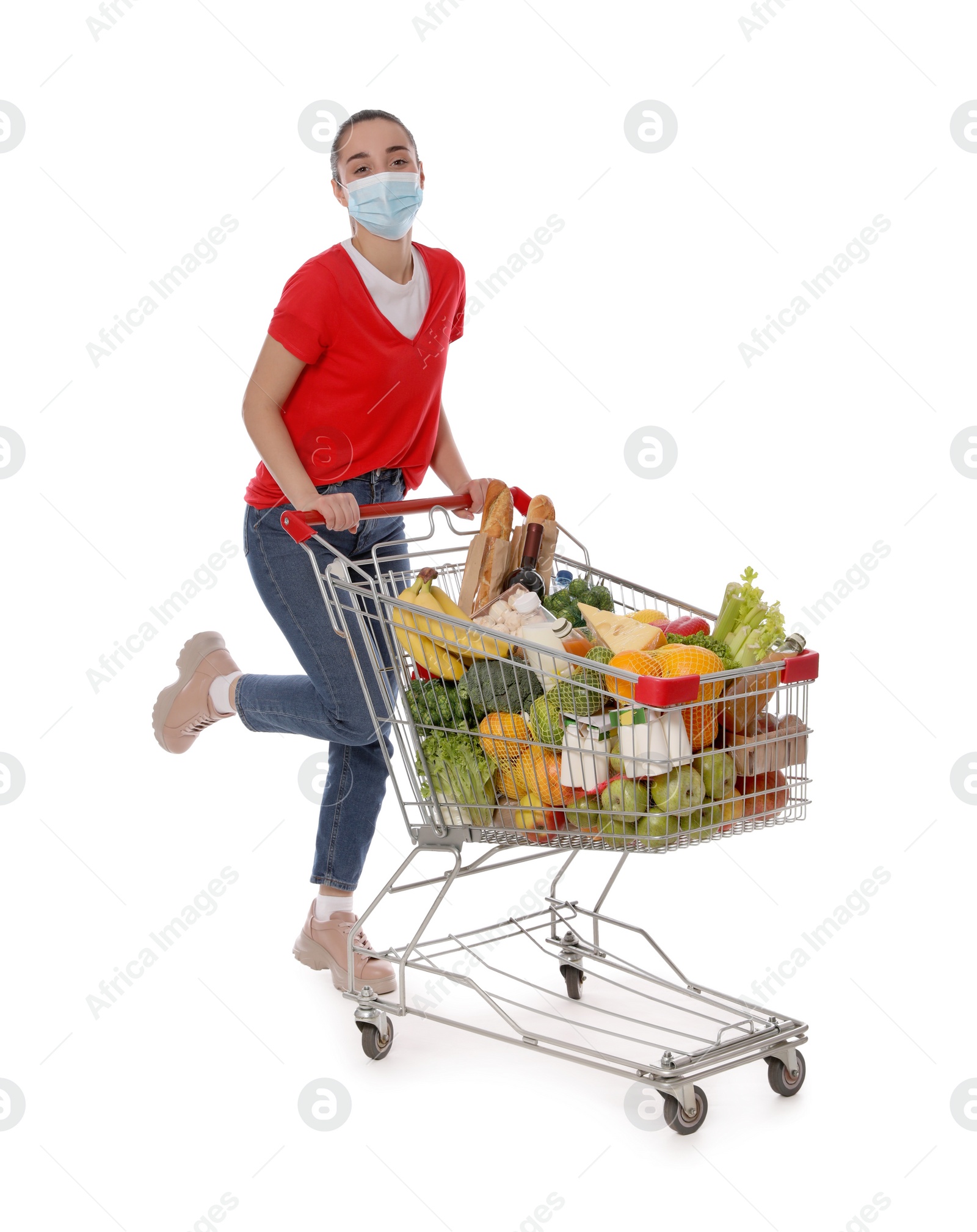 Photo of Woman with protective mask and shopping cart full of groceries on white background