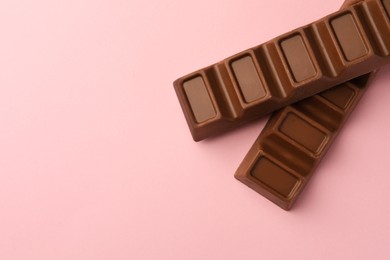 Delicious chocolate bars on pink background, flat lay. Space for text