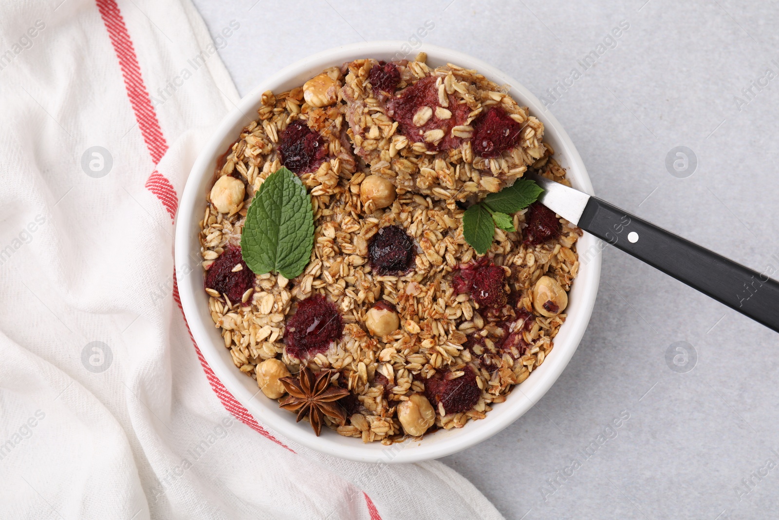 Photo of Tasty baked oatmeal with berries, nuts and anise star on light grey table, top view