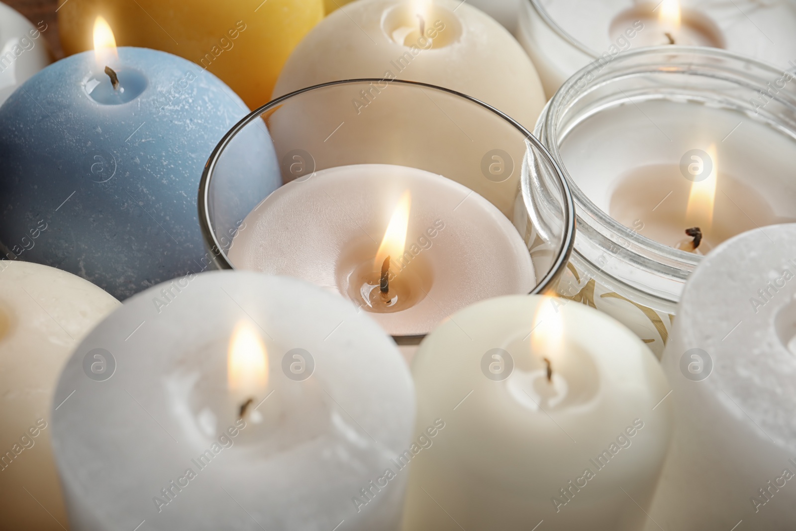 Photo of Burning wax candles of different shapes and colors, closeup