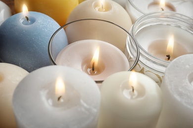 Photo of Burning wax candles of different shapes and colors, closeup