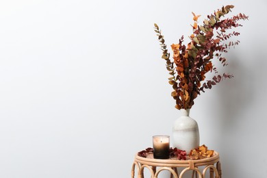 Photo of Vase with branches and candle on table near white wall, space for text