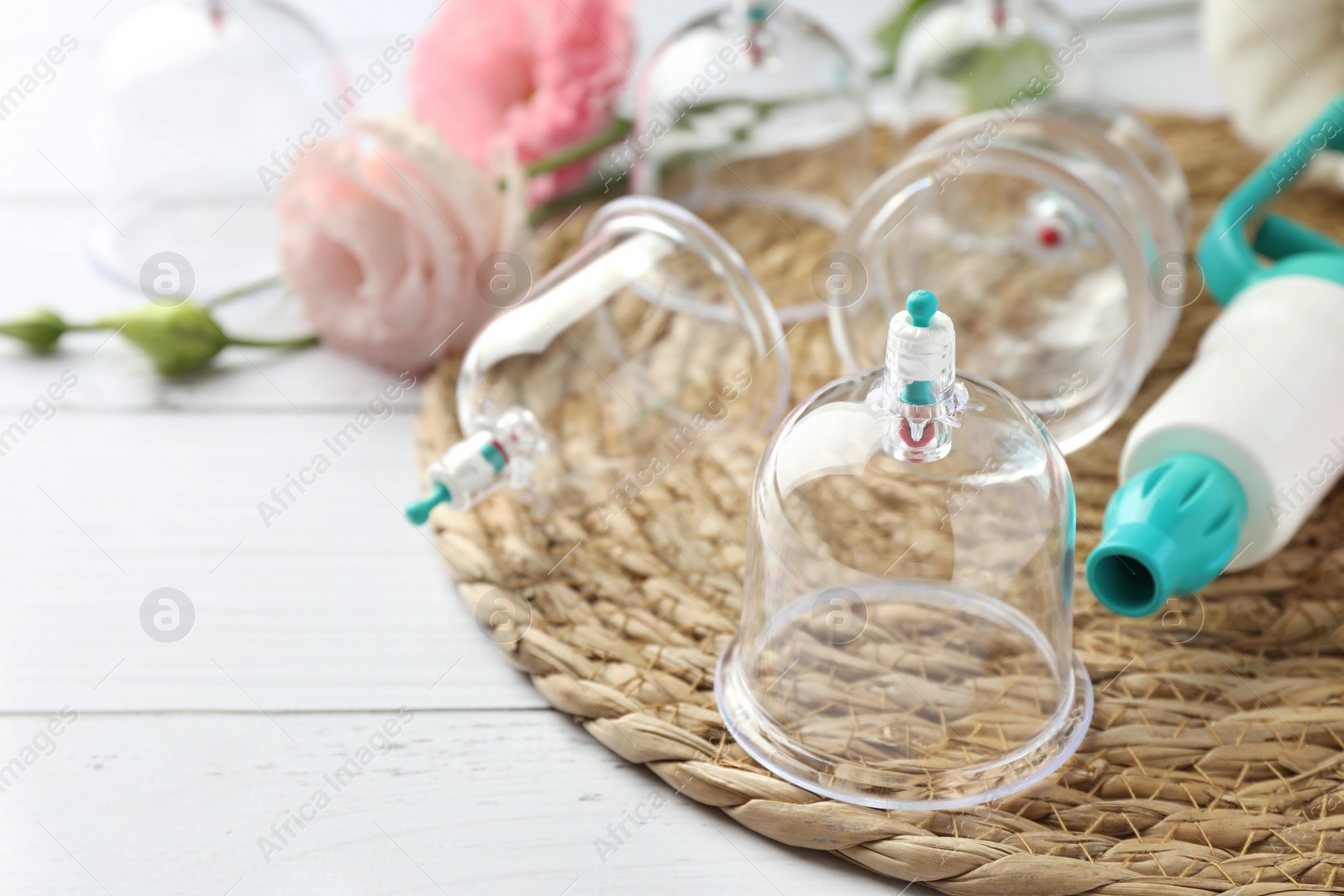 Photo of Cupping therapy. Plastic cups and hand pump on white wooden table, closeup. Space for text