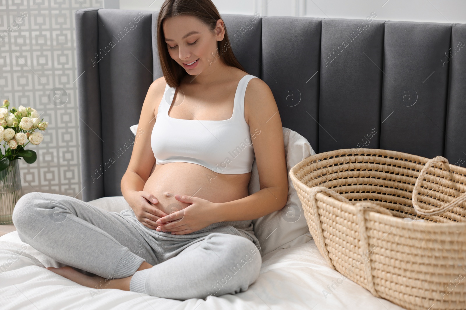 Photo of Beautiful pregnant woman sitting on bed indoors