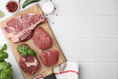 Photo of Flat lay composition with cut fresh beef meat and spices on white tiled table, flat lay. Space for text