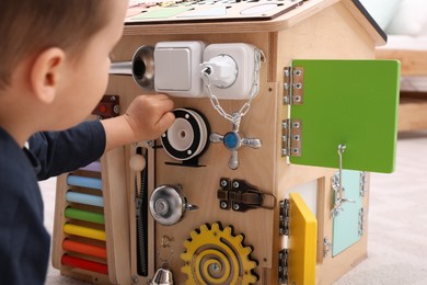 Little boy playing with busy board house on floor, closeup