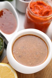 Photo of Different marinades in tableware on table, closeup