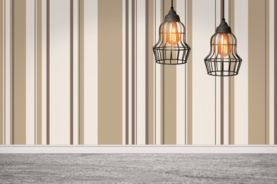 Image of Stylish pendant lamps hanging near striped wall in room