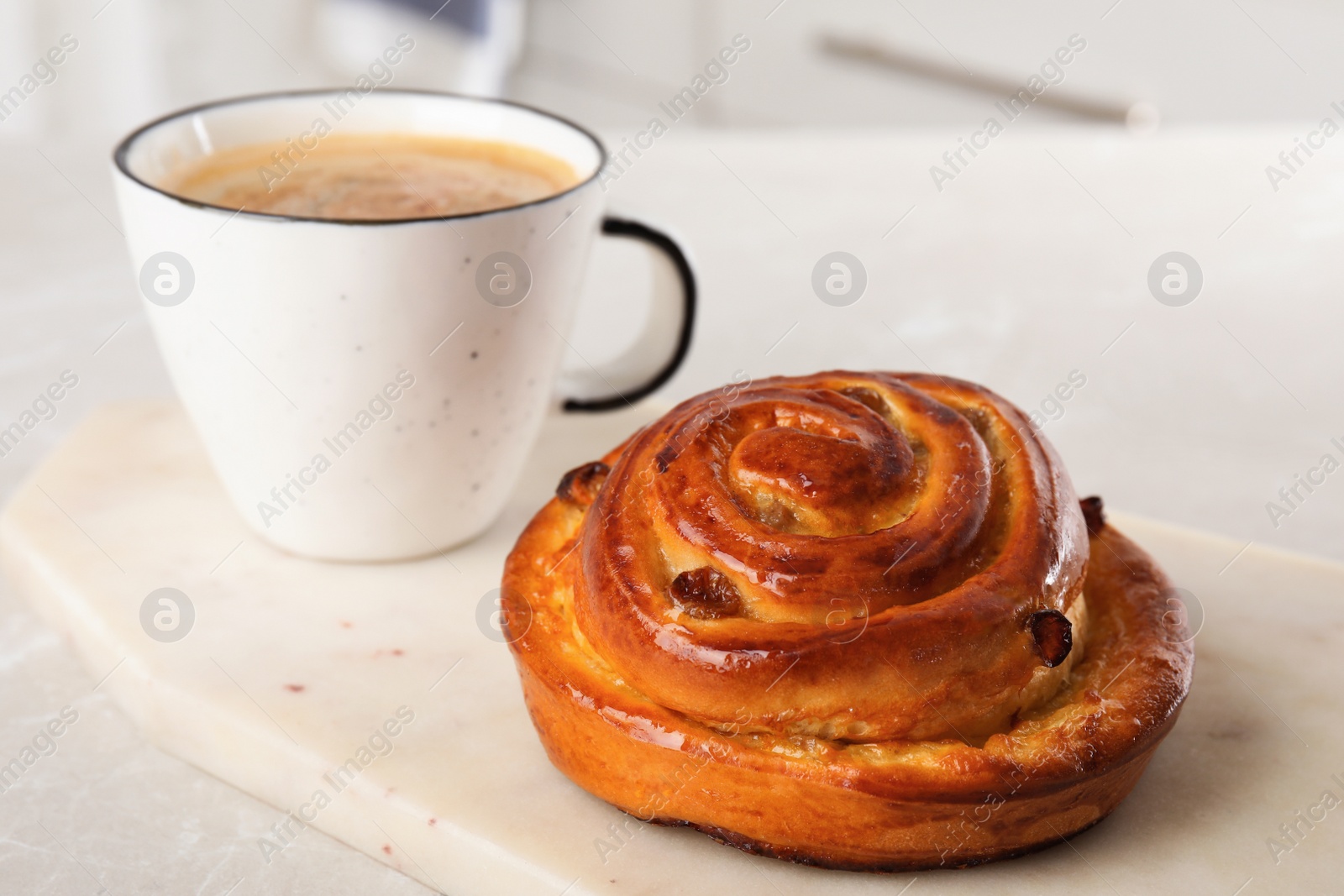 Photo of Delicious bun and coffee on light table. Sweet pastries