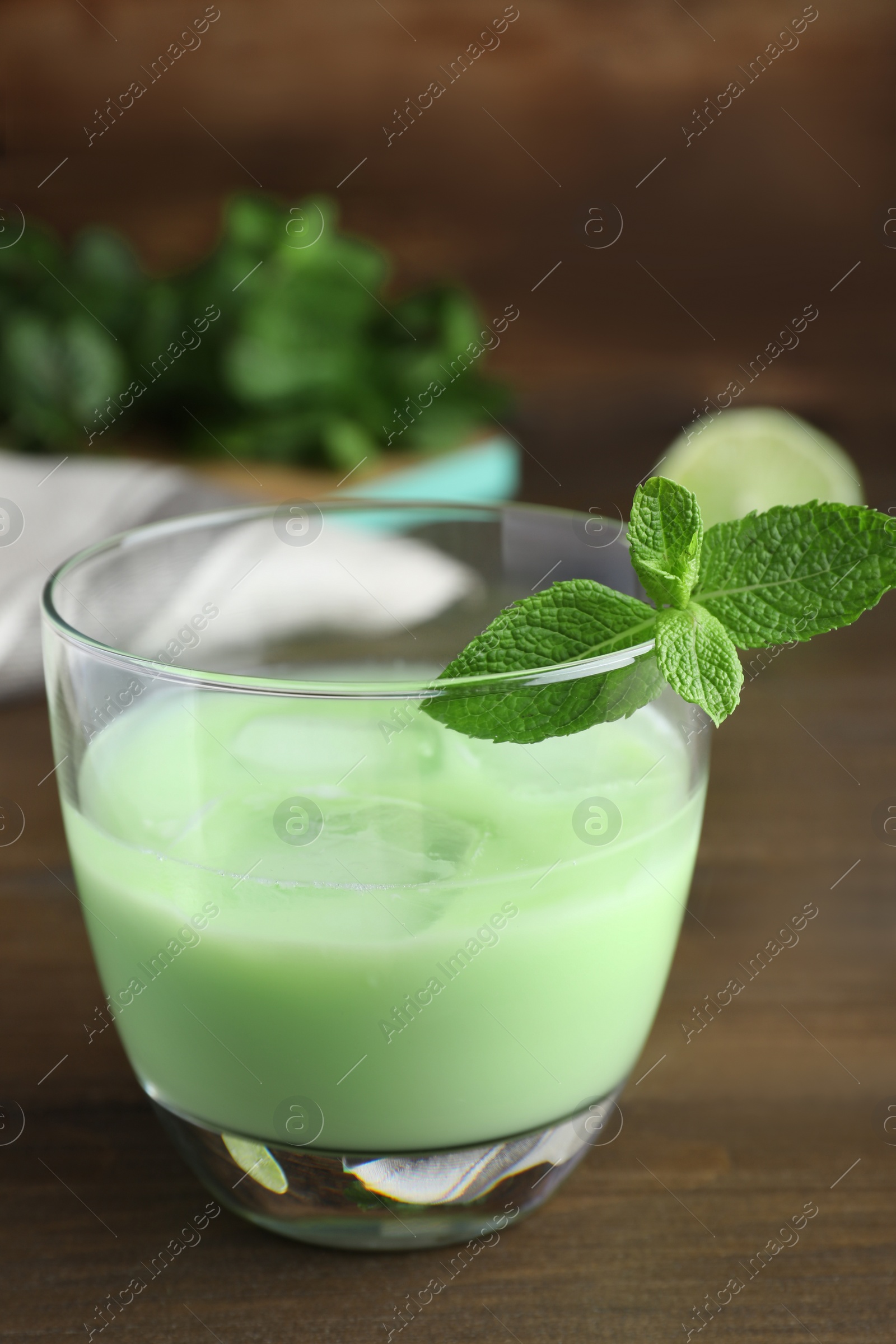 Photo of Delicious mint liqueur with green leaves on wooden table, closeup