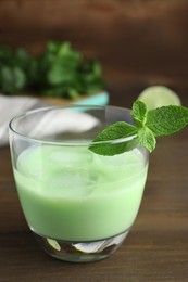 Delicious mint liqueur with green leaves on wooden table, closeup