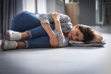 Photo of Lonely depressed woman lying on floor at home