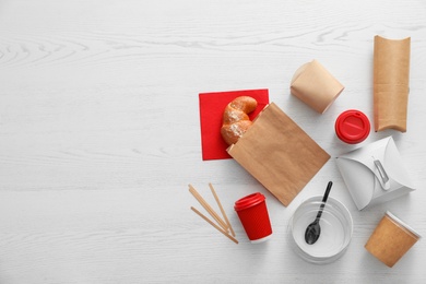 Flat lay composition with paper bag and different takeaway items on wooden background. Space for design