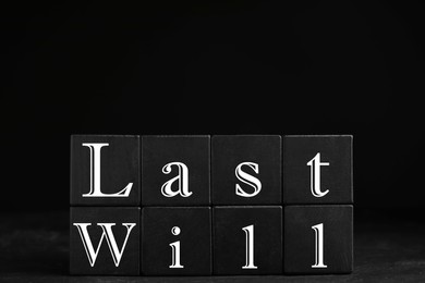 Photo of Black cubes with words Last Will on dark background