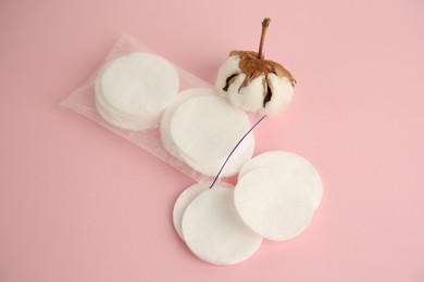 Photo of Plastic bag with cotton pads and flower on pink background