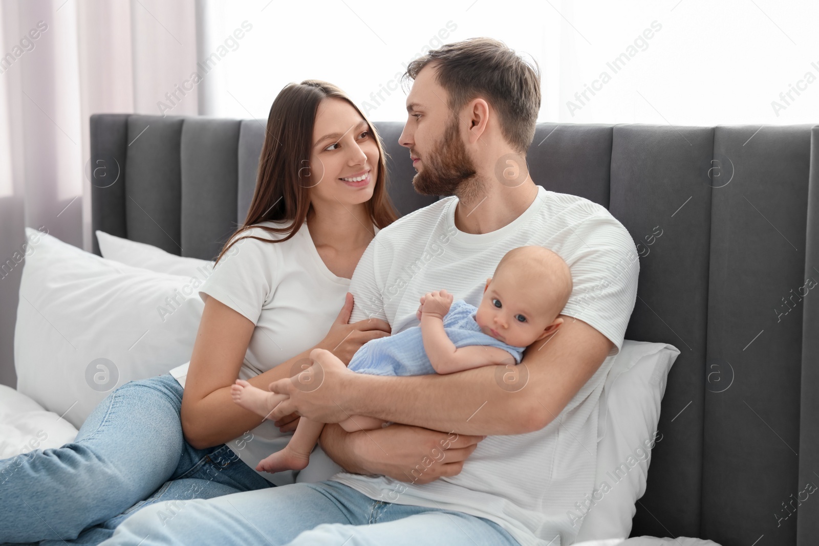 Photo of Happy family. Parents with their cute baby on bed indoors