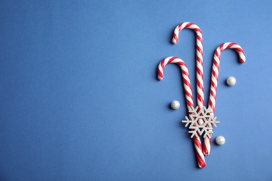 Photo of Candy canes on blue background, flat lay. Space for text