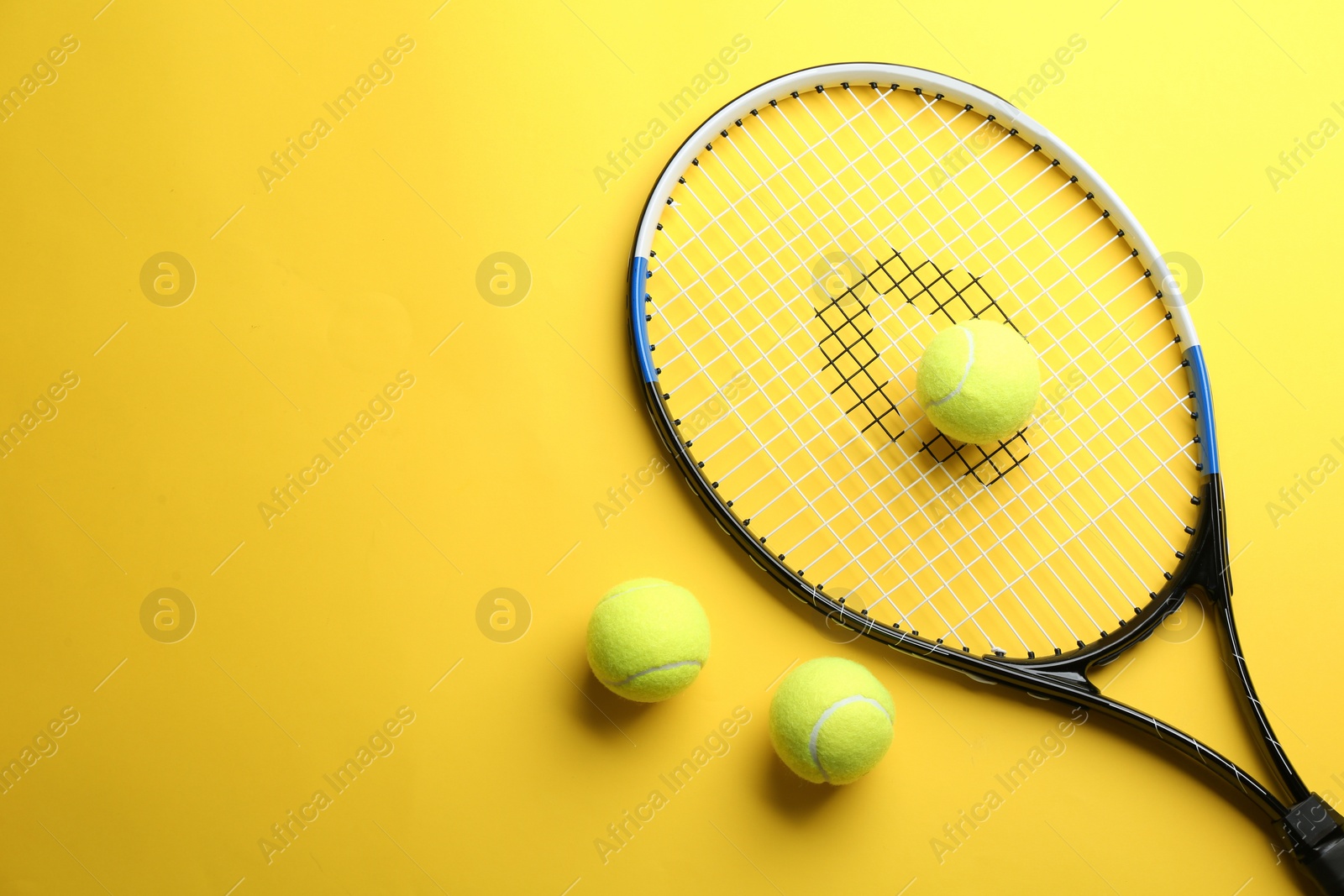 Photo of Tennis racket and balls on yellow background, flat lay. Space for text