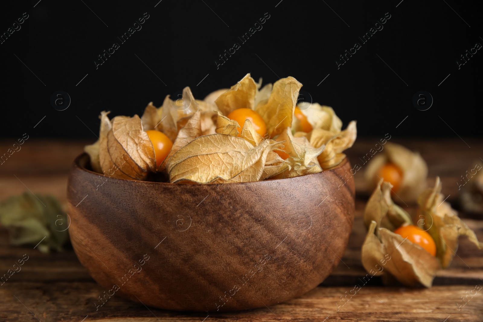 Photo of Ripe physalis fruits with dry husk on wooden table, closeup