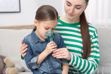 Mother helping her sick daughter with nebulizer inhalation at home