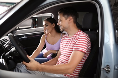 Photo of Young couple testing new car in salon