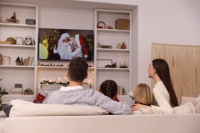 Photo of Family watching Christmas movie via TV in cosy room, back view. Winter holidays atmosphere