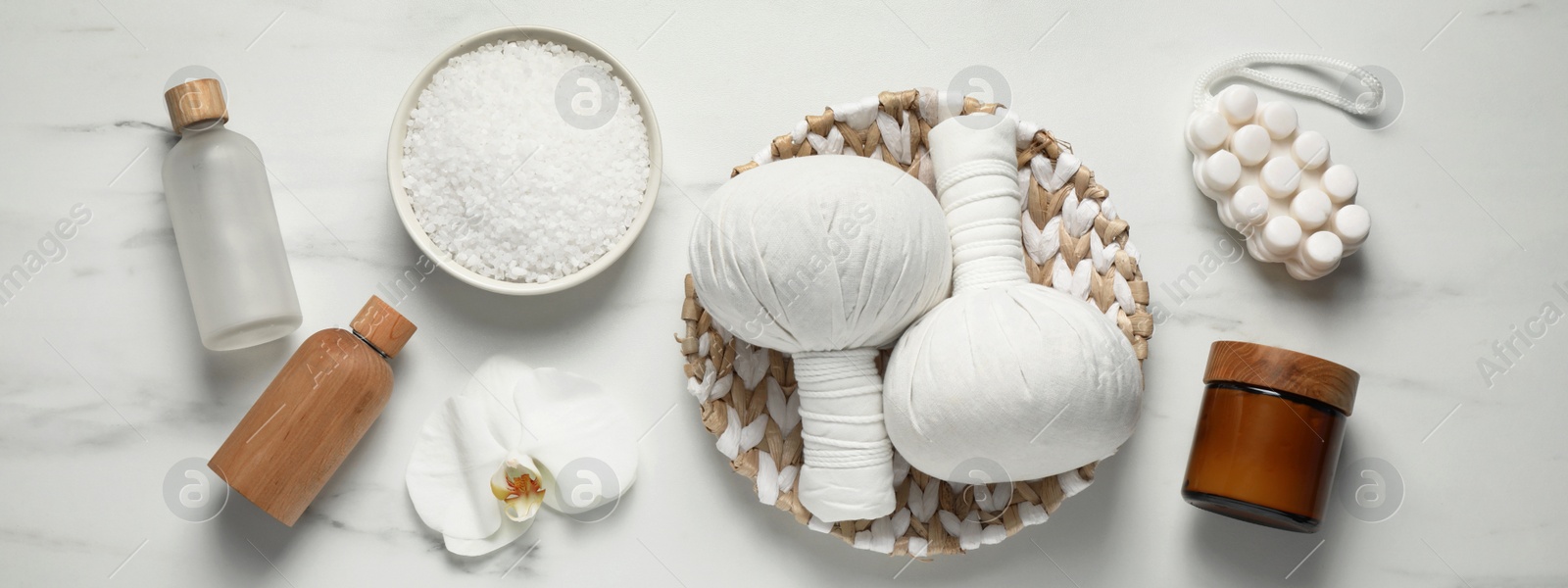 Image of Flat lay composition with herbal massage bags and other spa products on white marble table. Banner design