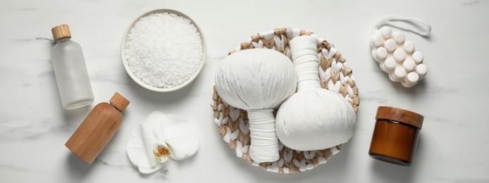 Image of Flat lay composition with herbal massage bags and other spa products on white marble table. Banner design