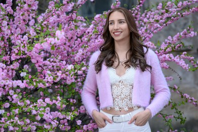 Photo of Beautiful young woman near blossoming sakura tree on spring day