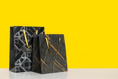 Photo of Stylish shopping paper bags on yellow background. Space for text