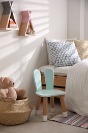 Cute little chair with bunny ears near bed indoors. Children's room interior