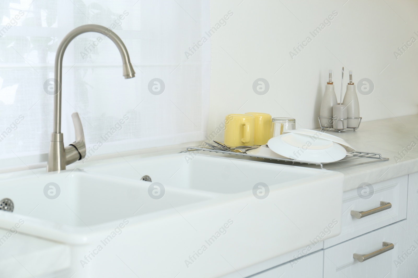 Photo of Clean dishes drying on rack in modern kitchen