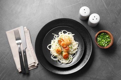 Photo of Delicious scallop pasta with green onion served on grey table, flat lay