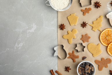 Photo of Flat lay composition with unbaked cookies and cutters on light grey marble table, space for text. Christmas biscuits