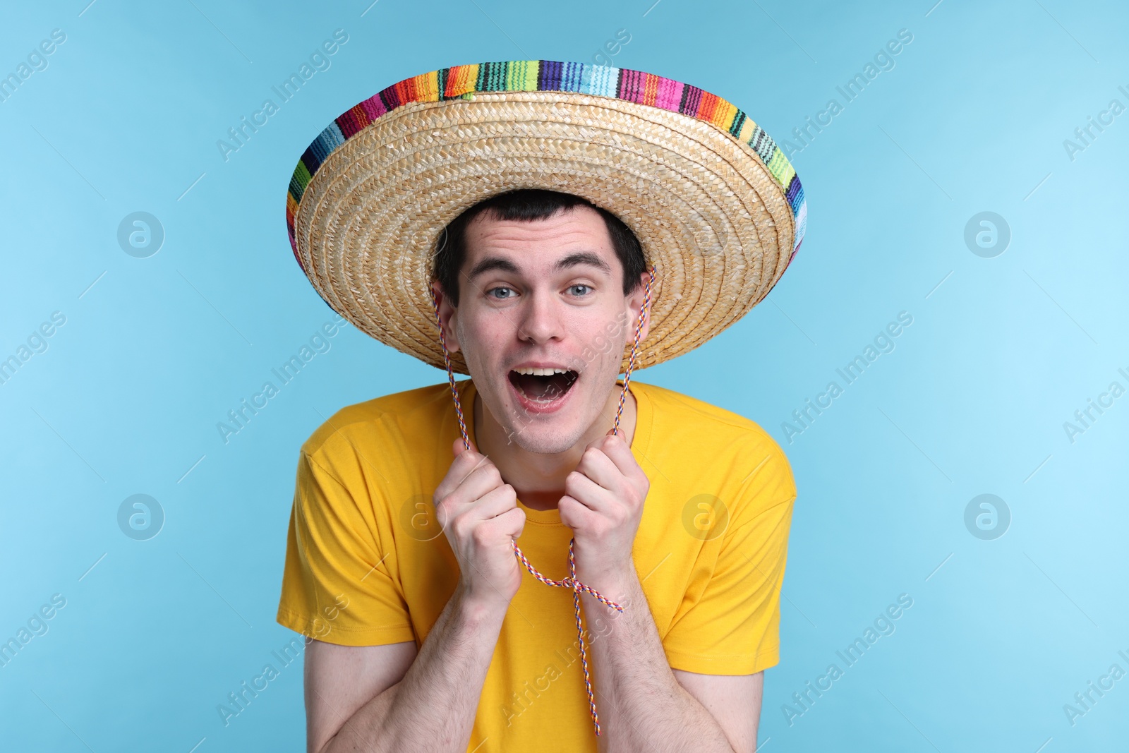 Photo of Young man in Mexican sombrero hat on light blue background