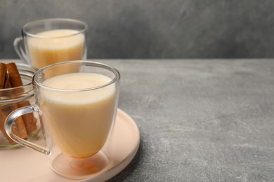 Photo of Delicious eggnog with cinnamon on light grey table. Space for text
