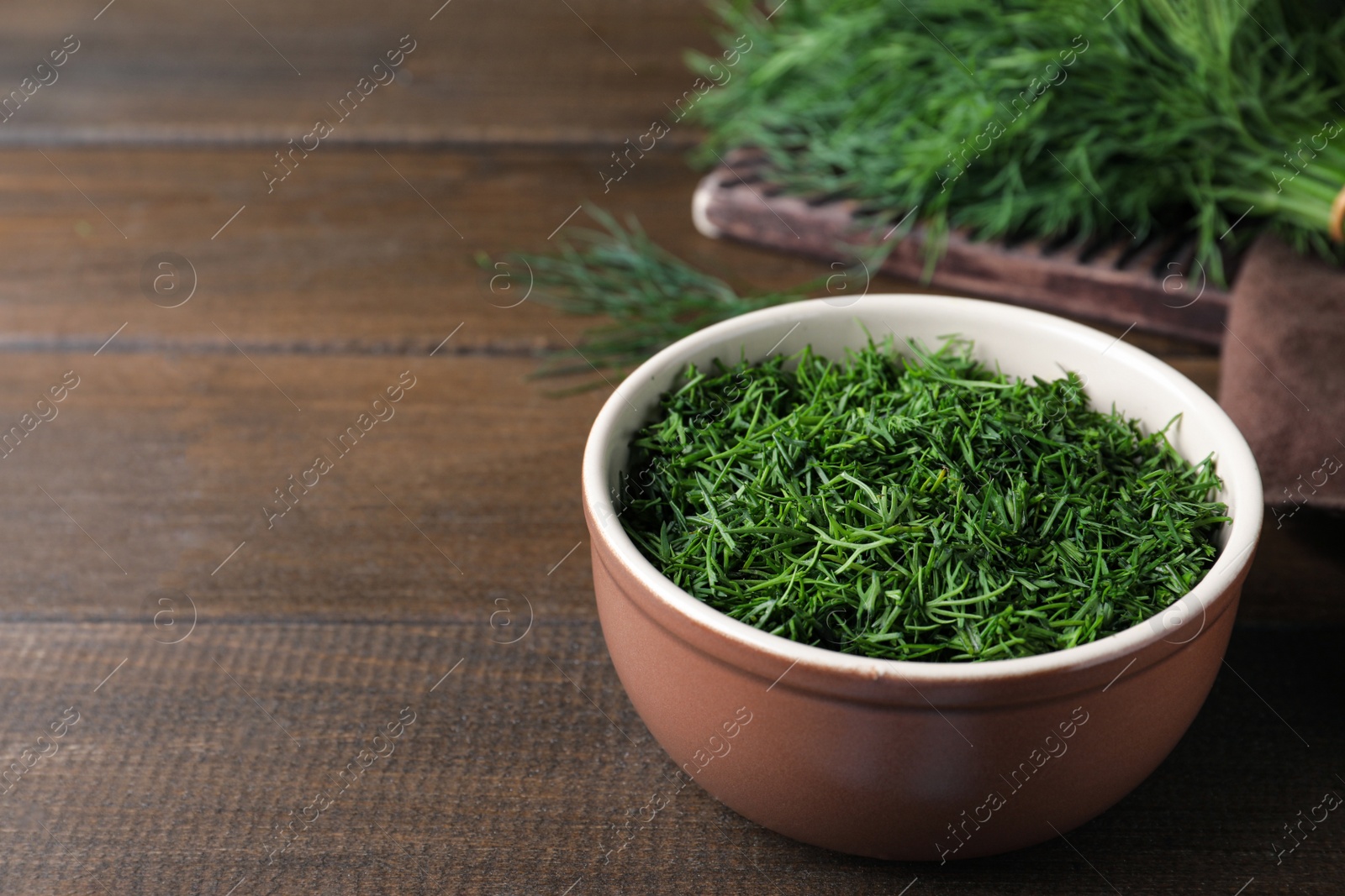 Photo of Bowl of fresh dill on wooden table, space for text