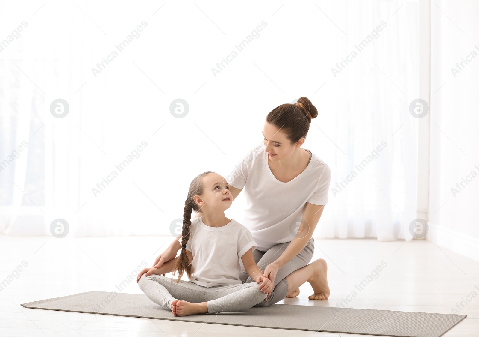 Photo of Young mother with little daughter practicing yoga at home