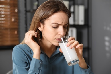 Photo of Woman taking medicine for hangover in office