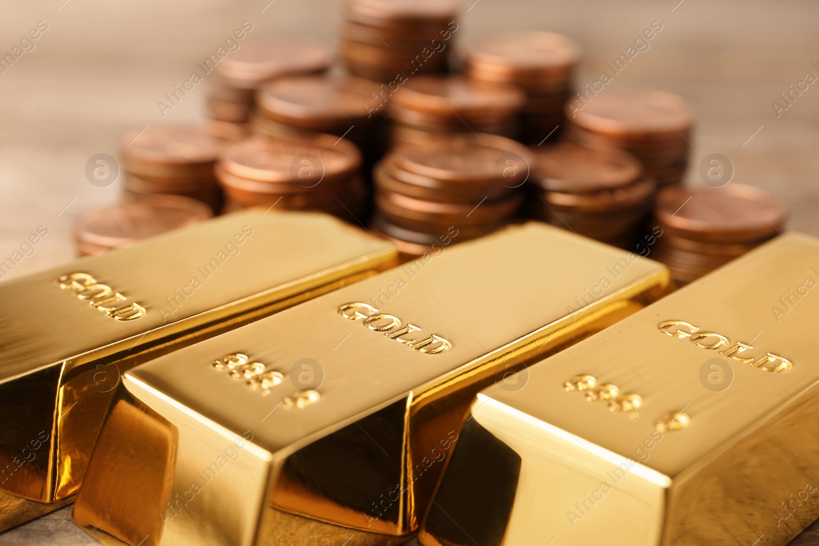 Photo of Shiny gold bars and coins on table, closeup